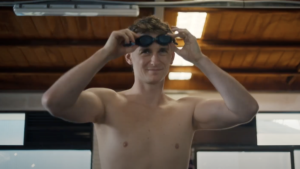 Adam Bowes as Alex putting on swim goggles in a scene from Diving In