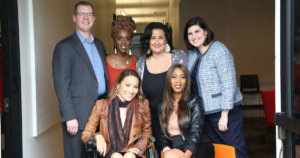 Six diverse people with disabilities smiling together inside a hallway