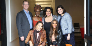 Six diverse people with disabilities smiling together inside a hallway