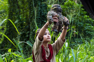 Kaylee Hottle in a scene from Godzilla vs. Kong holding up an artifact in a forest