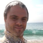 Shlomo Meyers smiling headshot on the beach with the ocean behind him