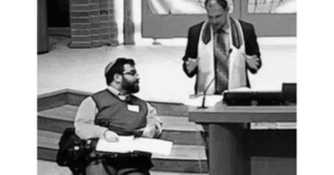 Matan Koch in a synagogue next to a rabbi with the Bimah brought down to the bottom of the staircase