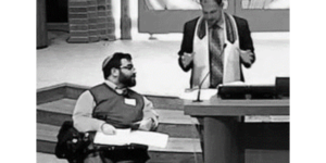 Matan Koch in a synagogue next to a rabbi with the Bimah brought down to the bottom of the staircase