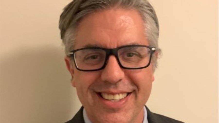 Craig Leen smiling headshot wearing glasses and a suit and tie