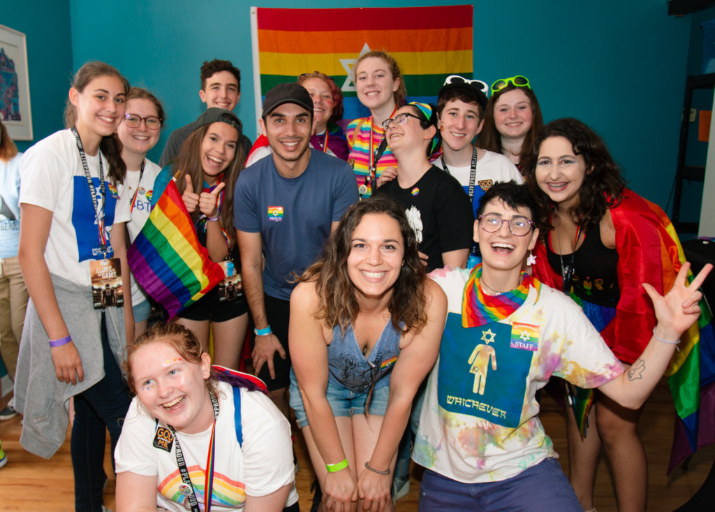A group of teens at a JQ International event wearing and holding rainbow flag clothes and items