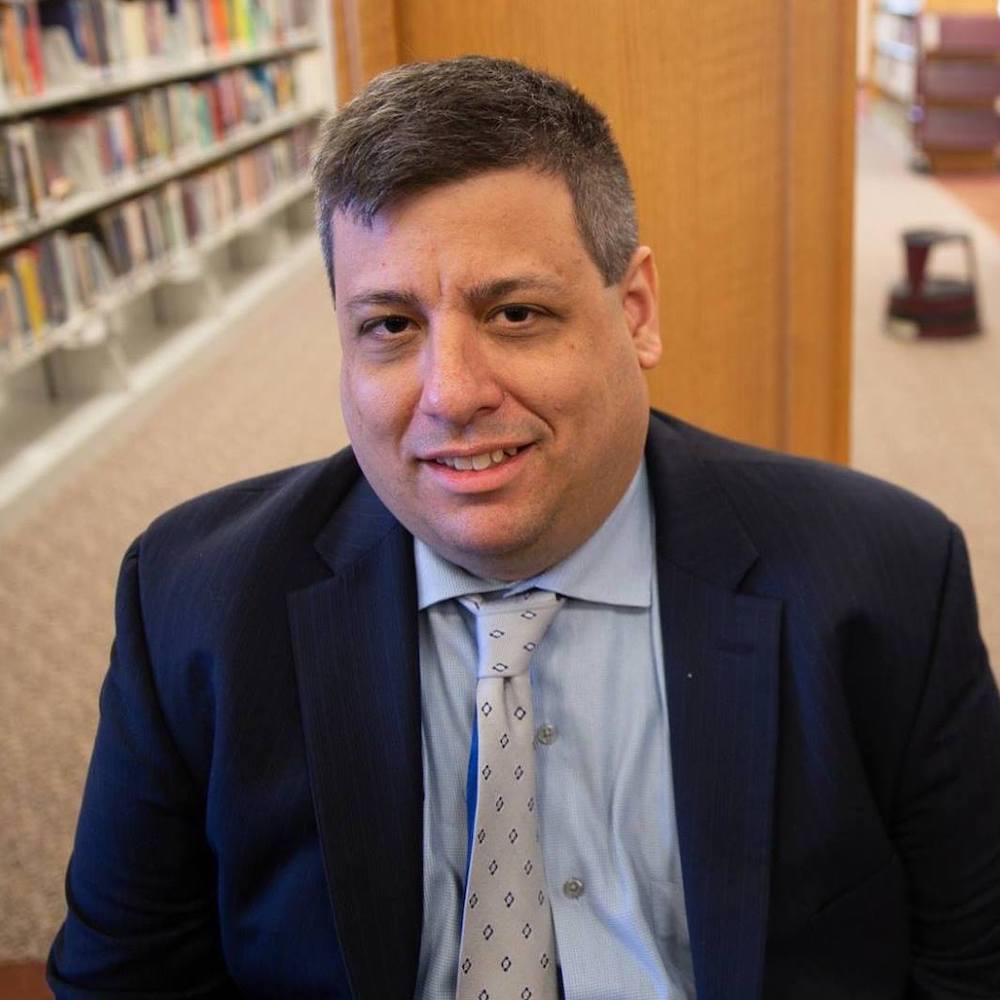 Michael Gilberg smiling headshot wearing a suit and tie