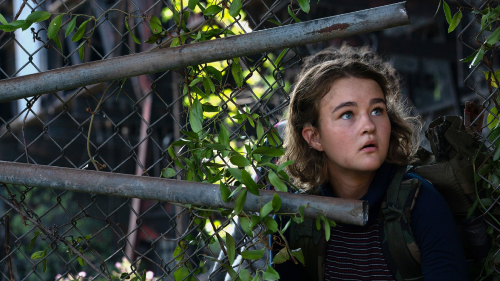 Millicent Simmonds in the woods behind a fence in a scene from A Quiet Place Part II