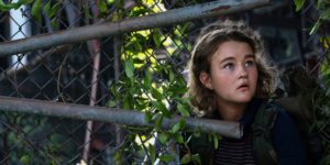 Millicent Simmonds in the woods behind a fence in a scene from A Quiet Place Part II