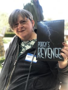 Erika Abbott smiling holding a copy of her book, Porgy's Revenge.