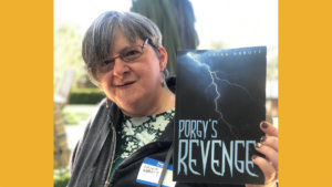 Erika Abbott smiling holding a copy of her book, Porgy's Revenge.