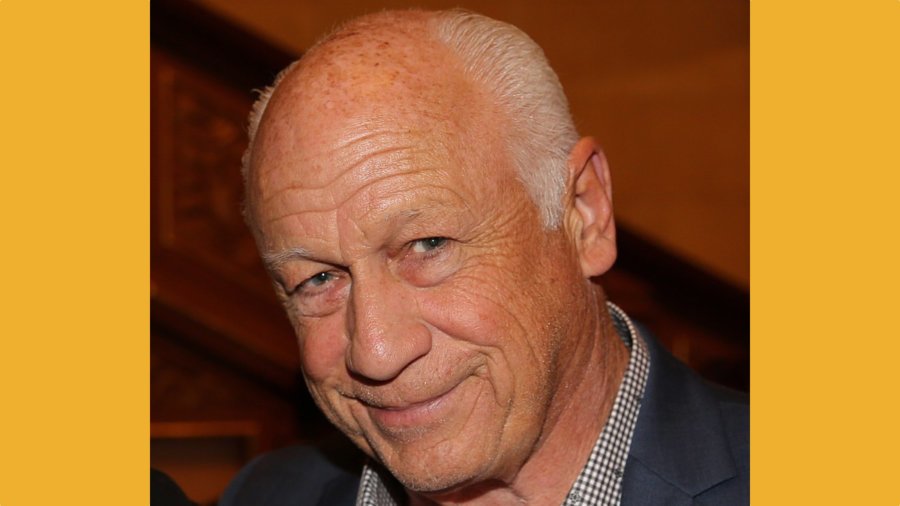 Joey Travolta smiling headshot wearing a suit jacket.