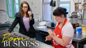 Collette Divitto wearing an apron, eating cookies with her mom inside the kitchen