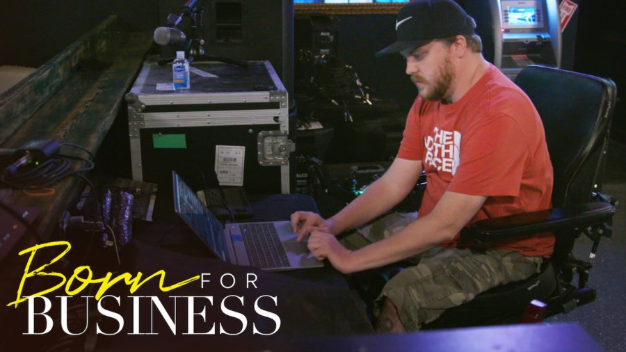 Chris working tech at a concert venue in a scene from Born For Business. Show logo in bottom left.