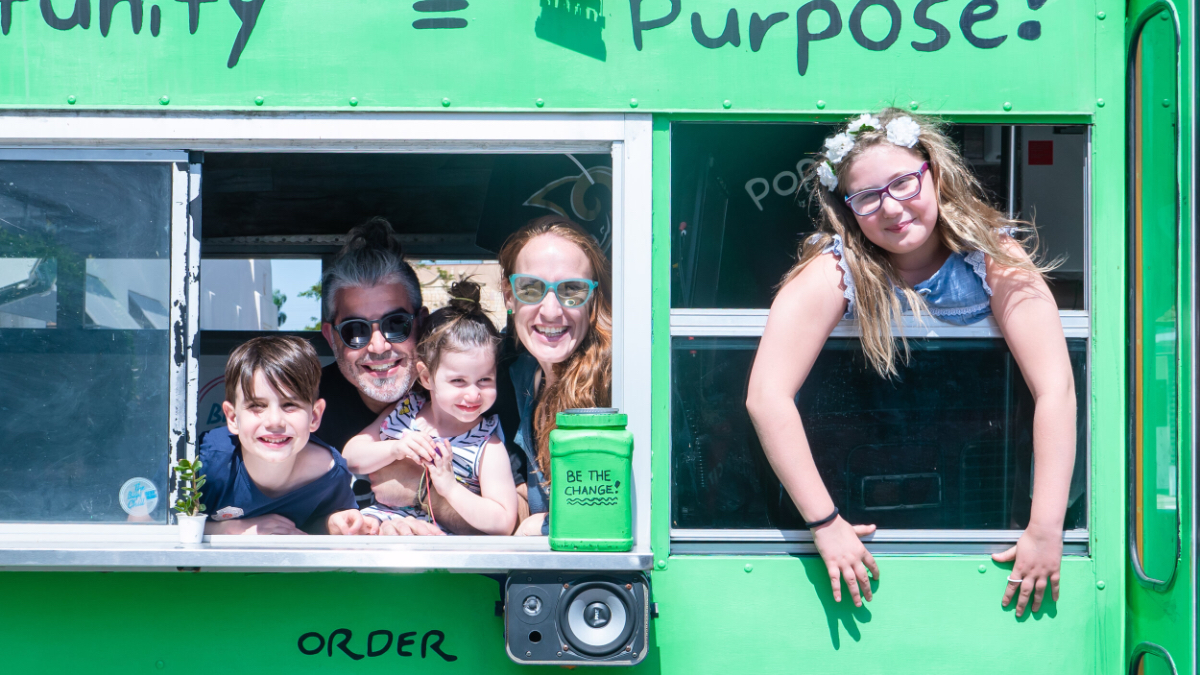 the Chernotsky family looking out the windows in a green bus, smiling