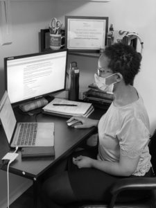 Woman working at computers with mask on