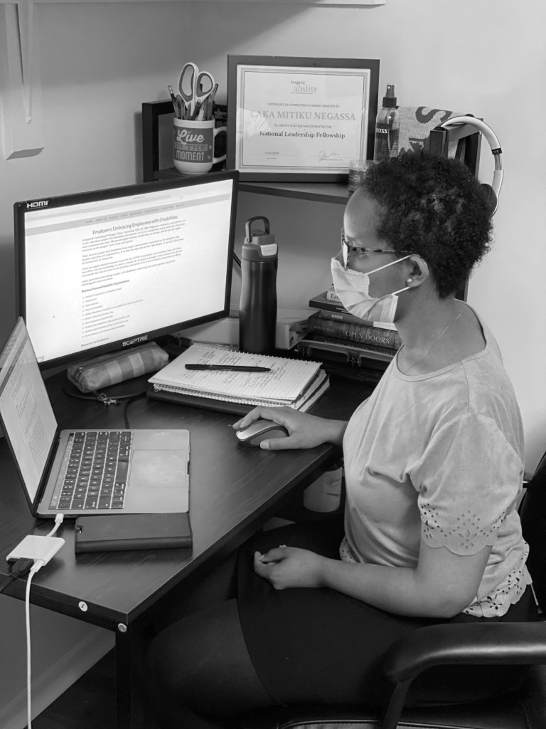 Laka Negassa working at computers with mask on