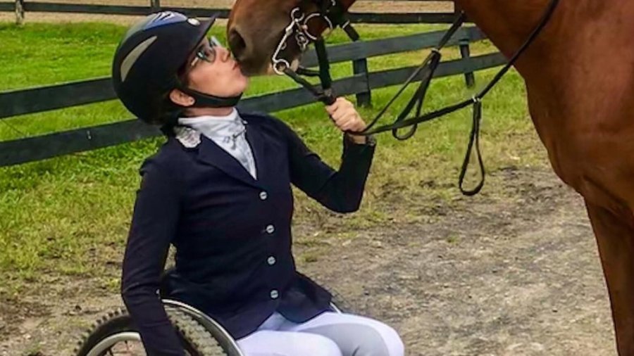 Alanna Flax-Clark with a horse kissing her face. Flax-Clark is a wheelchair user.