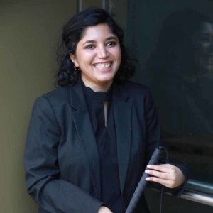 Baksha Ali holding a white cane, smiling