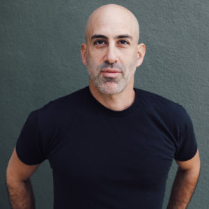 headshot of Douglas Ridloff wearing a blac t-shirt