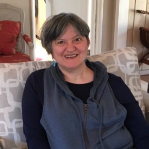 Erika Abbott smiling headshot seated on a couch