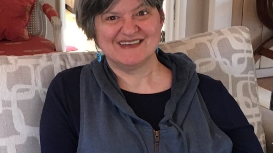 Erika Abbott smiling headshot seated on a couch