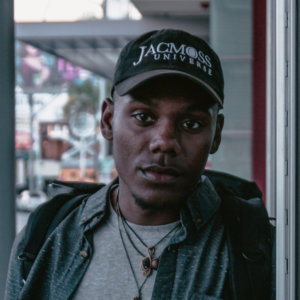 Jacquill Moss headshot wearing a hat that says JacMoss Universe on it.