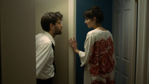 Dakota Johnson and a man in a scene from Cha Cha Real Smooth, looking at each other.