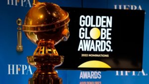 A golden globe statue next to a screen with the logo for Golden Globe Awards and text reading 2022 nominations
