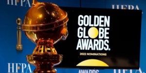 A golden globe statue next to a screen with the logo for Golden Globe Awards and text reading 2022 nominations
