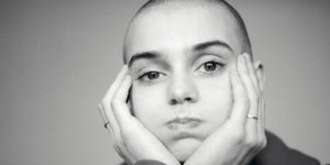 Black and white photo of Sinead O'Connor with her head in her hands.