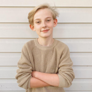 Hartley Bernier smiling with his arms crossed in front of a wall