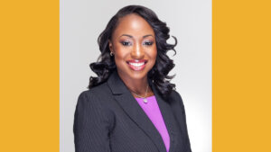 Courtney Munnings smiling headshot wearing a black suit jacket and pink shirt