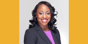 Courtney Munnings smiling headshot wearing a black suit jacket and pink shirt