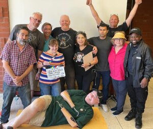 Group photo of the cast and crew behind Taco Tuesday, with John Lawson lying on the floor