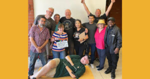 Group photo of the cast and crew behind Taco Tuesday, with John Lawson lying on the floor