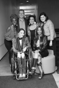A diverse group of six RespectAbility Hollywood team members and volunteers smile together in a hallway.