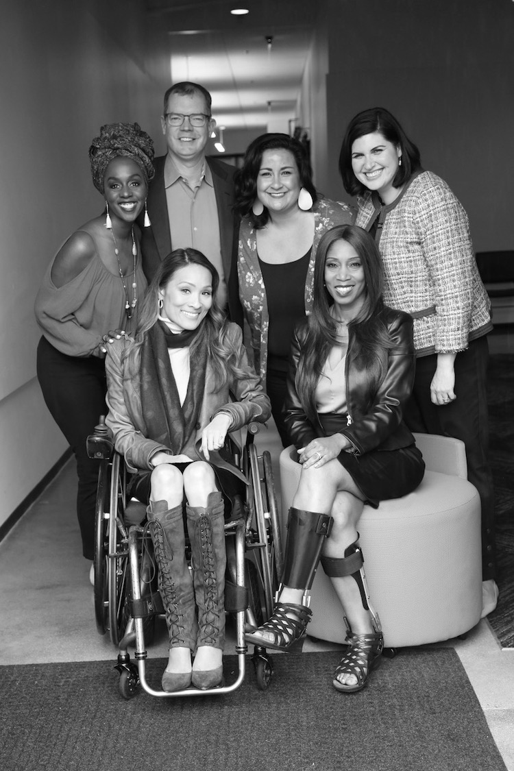 A diverse group of RespectAbility Hollywood team members smile together in a hallway