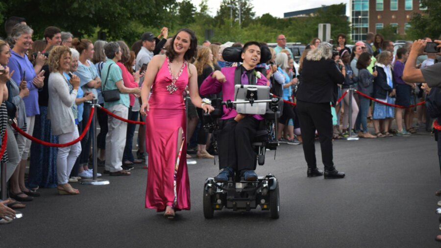 Samuel Habib and a young woman in a dress moving through a crowd of people cheering them on in a scene from My Disability Roadmap