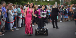 Samuel Habib and a young woman in a dress moving through a crowd of people cheering them on in a scene from My Disability Roadmap