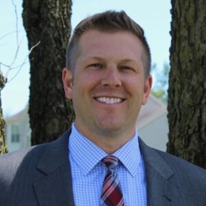 Eric Ochmanek smiling headshot wearing a suit and tie