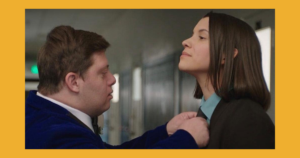 Zack Gottsagen adjusts Katie Burton's tie in a scene from At Last