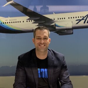 Steve Nelson smiling in front of a photo of an airplane