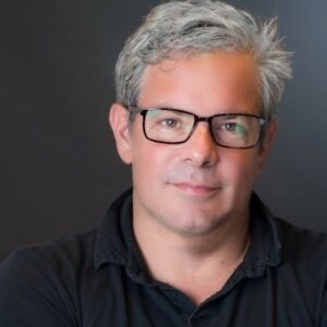 Tom Newman headshot wearing glasses and a polo shirt