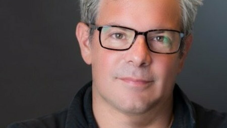 Tom Newman headshot wearing glasses and a polo shirt