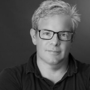 Tom Newman headshot wearing glasses and a polo shirt