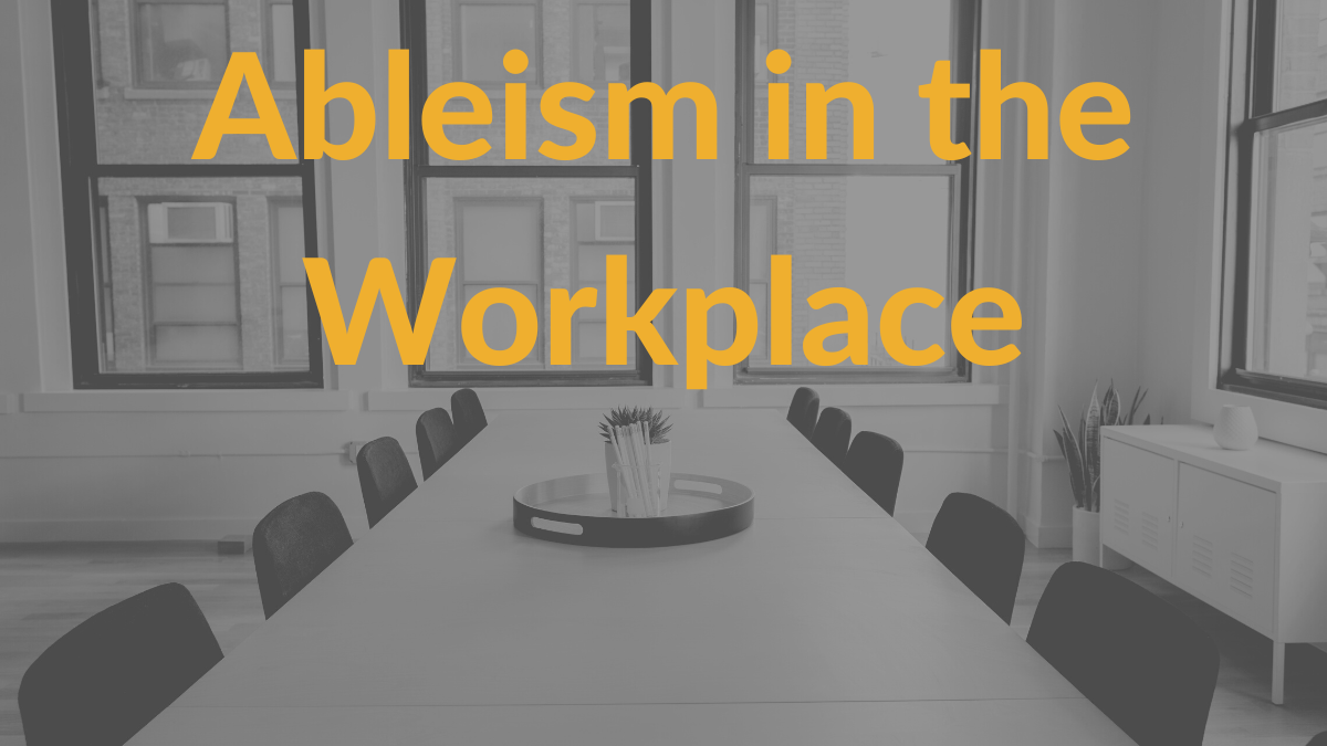 A conference room table in an office with empty chairs around it. Text: Ableism in the workplace.