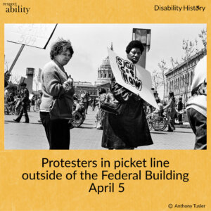 Black and white photo of picket line of protesters outside the Federal Building. Two protesters are in the center of photo and one is holding sign that says, “Sign 504 Now.” Protestors walking and in wheelchairs can be seen protesting in the background in front of City Hall. Text: Protesters in picket line outside of the Federal Building. April 5. Source: Anthony Tusler.