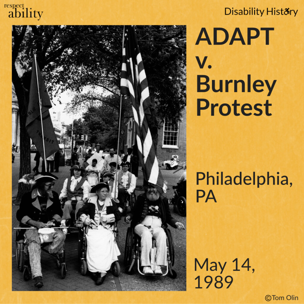 Black and white photo of group of protesters in wheelchairs marching down a sidewalk wearing revolutionary attire. One protester is holding the ADAPT American flag. Text: ADAPT v. Burnley Protest. Philadelphia, PA. May 14, 1989. Source: Tom Olin.