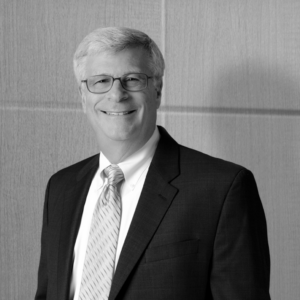 Black and white photo of the late Bobby Silverstein smiling wearing a suit and tie