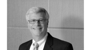 Black and white photo of the late Bobby Silverstein smiling wearing a suit and tie